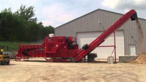 A large Rotochopper electric powered grinder depositing mulch from ground wooden pallets from a discharge chute.