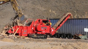 A Rotochopper B-66 horizontal grinder processing Construction and Demolition wood at a landfill with another machine.