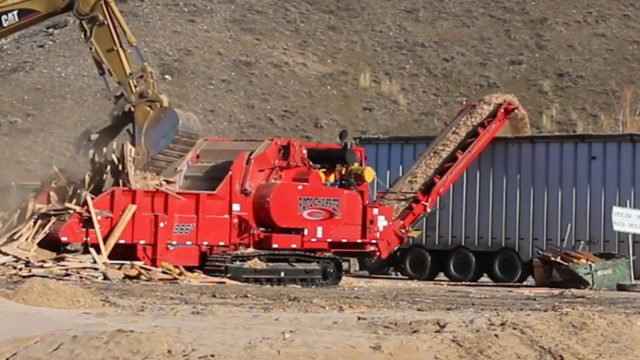 A Rotochopper B-66 horizontal grinder processing Construction and Demolition wood at a landfill with another machine.