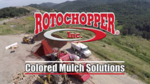 A Rotochopper grinding machine at a mulch yard with a text overlay over the image saying "Colored Mulch Solutions."