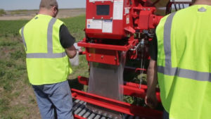 Two men working outdoors with a Rotochopper machine used for bagging mulch.