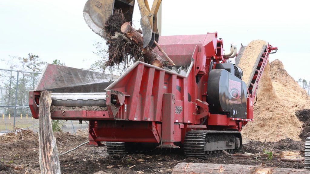 A Rotochopper B66 L-series horizontal grinder is shown in action breaking down large segments of hurricane storm debris into smaller debris.