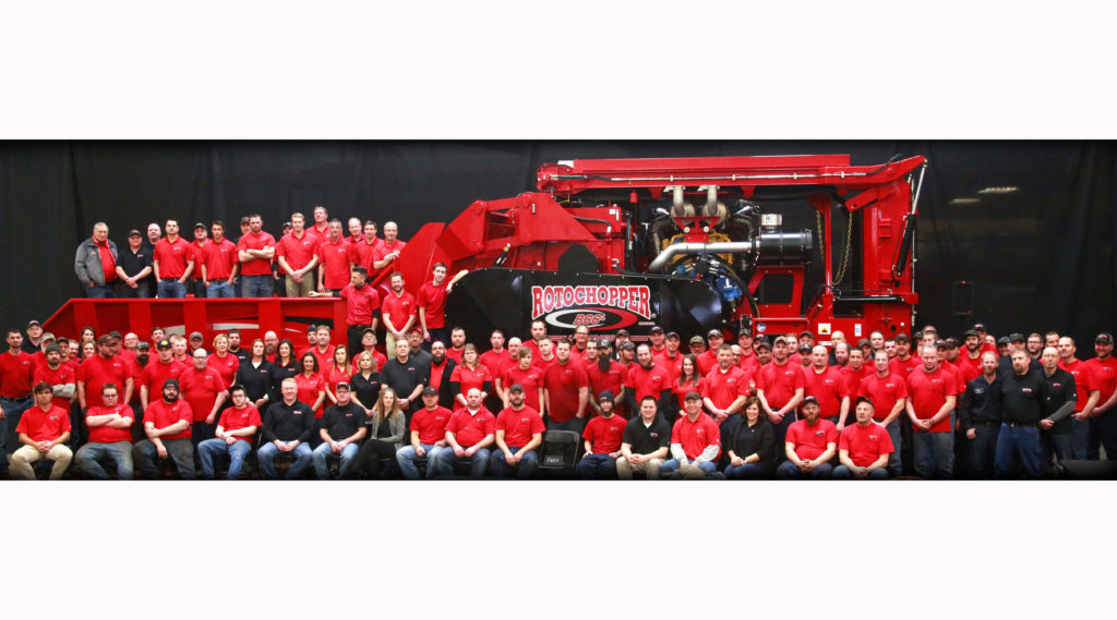 Rotochopper's employees posing for a photo together in front of one of their machines at their facility in MN.