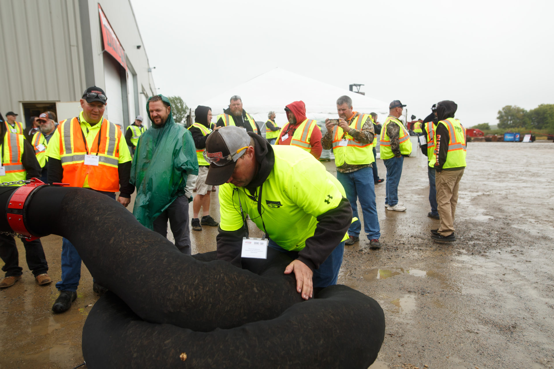 Man outside demonstrating erosion sock attachment for the Rotochopper GB-250 to others outdoors during demo day.