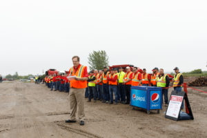 Men are standing together outside to watch the Rotochopper CEO get ready to present during Rotochopper's demo day event.