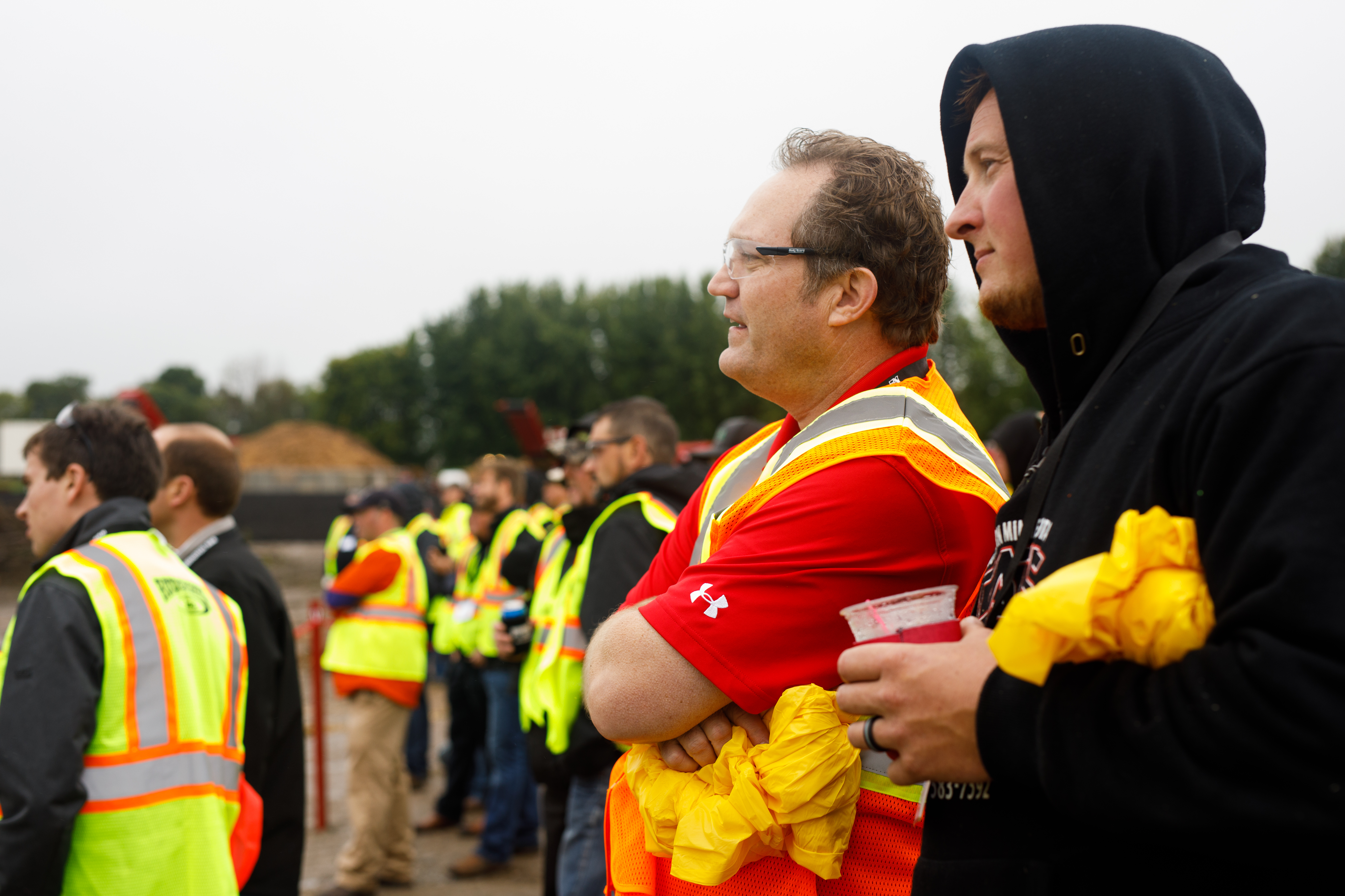 A group of men wearing safety vests, all paying close attention to a demonstration at Rotochopper's demo day event.