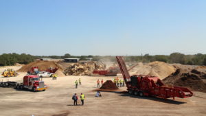 Zoomed out shot of people working and multiple Rotochopper machines working at Rotochopper Texas Field Day surrounded by piles.