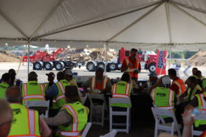 Large group of men with safety vests are all seated and paying attention to a man speaking at Rotochopper's field day event.