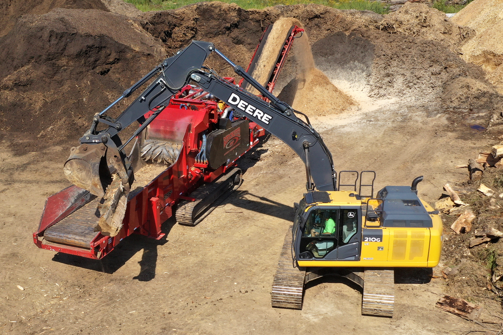 A Rotochopper horizontal grinder being mechanically loaded with logs.