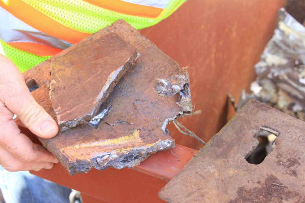 Hand holding a large, piece of metal that was stopped from going through the grinding champer by the StopWatch system.