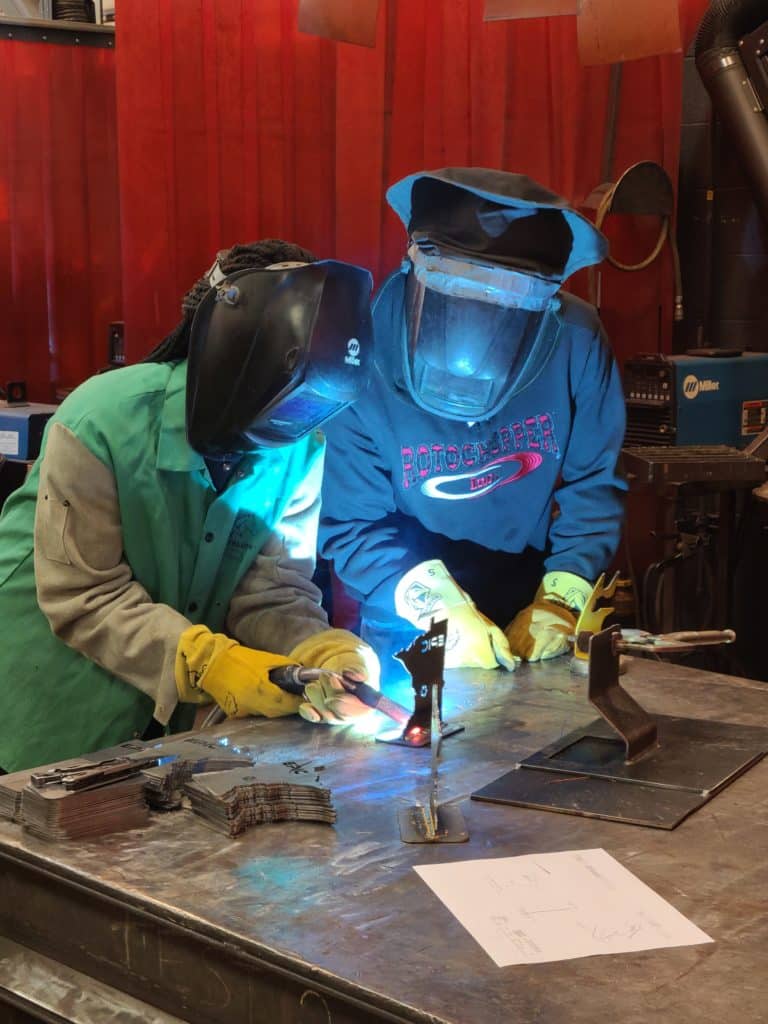 EPIC 2022 Rotochopper employee helping student learn how to weld