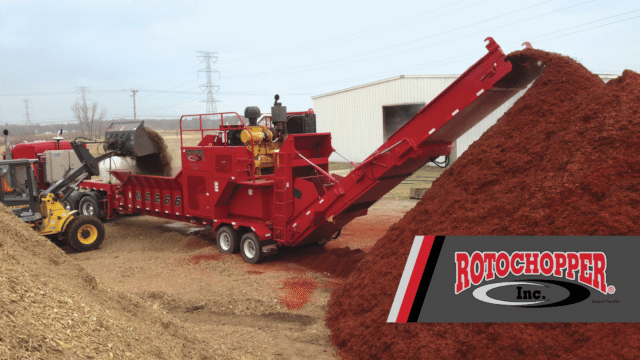 A Rotochopper grinder piles colored mulch on an industrial waste management site.