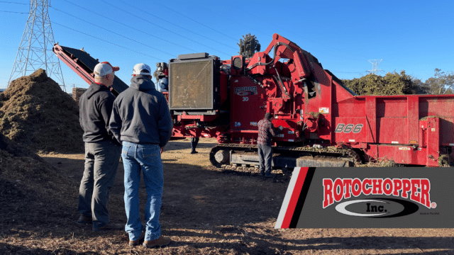 A Rotochopper grinder in the background of the shot while two operators discuss.