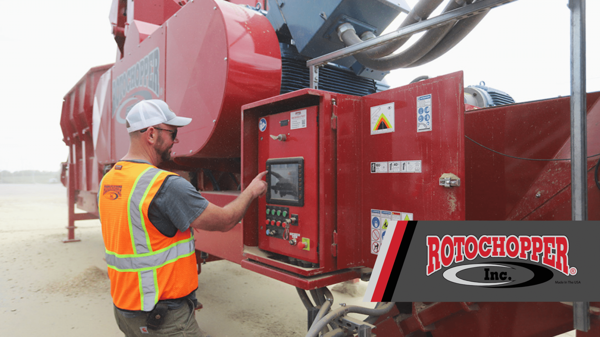 A service technician checks the control panel of a Rotochopper horizontal grinder; the Rotochopper logo sits in the bottom right corner.