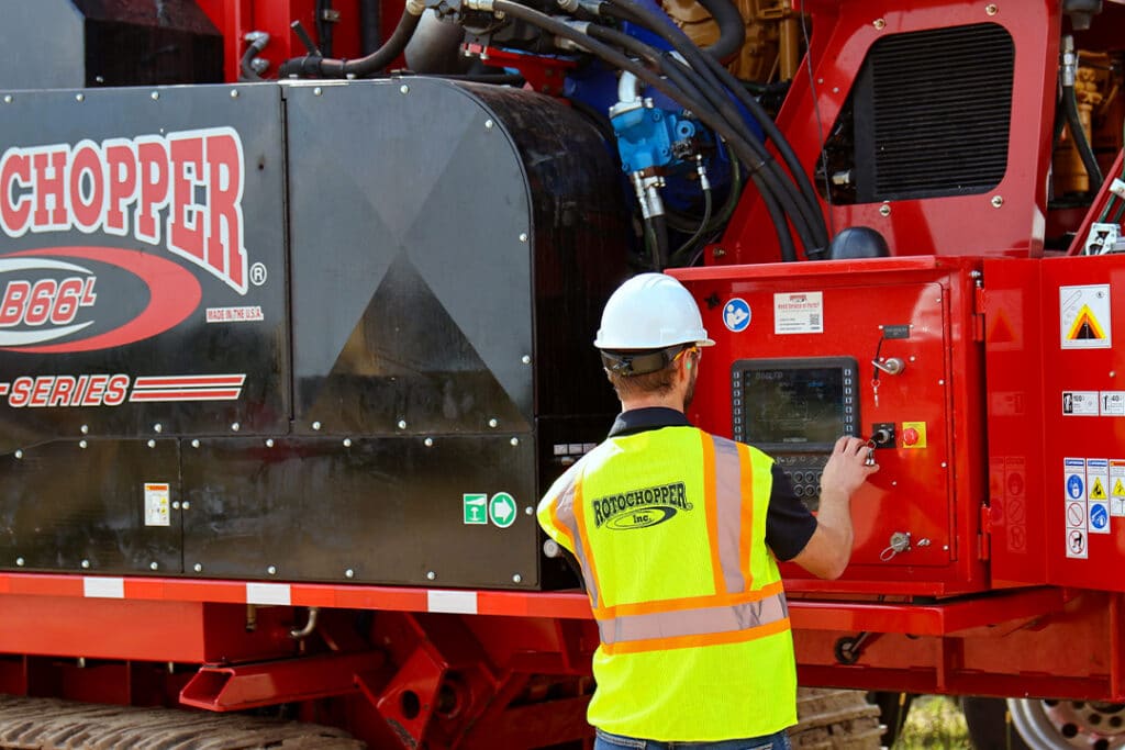 Rotochopper service technician inspecting the control panel of a horizontal grinder